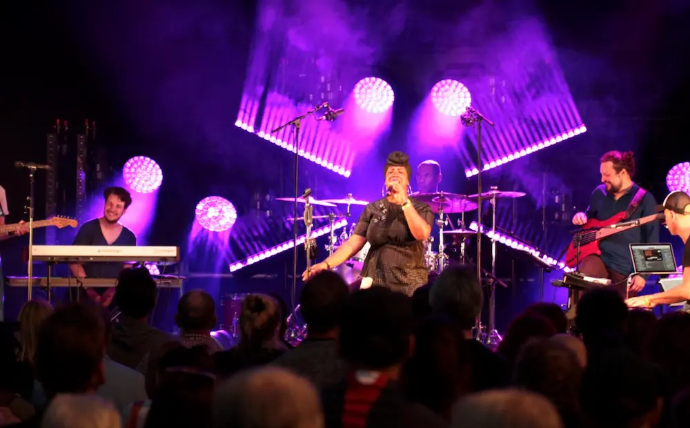 Sängerin performt vor live Publikum, mit Band im Hintergrund auf einer Bühne