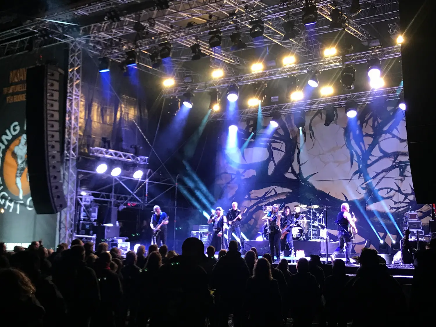 Eine Gruppe von Künstlern steht auf einer hell beleuchteten Bühne und performt live vor hunderten Gästen